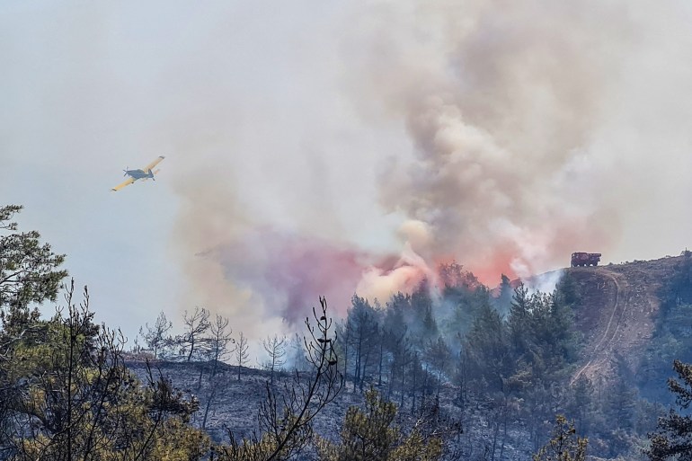 A firefighting aircraft drops water on a wildfire near Marmaris