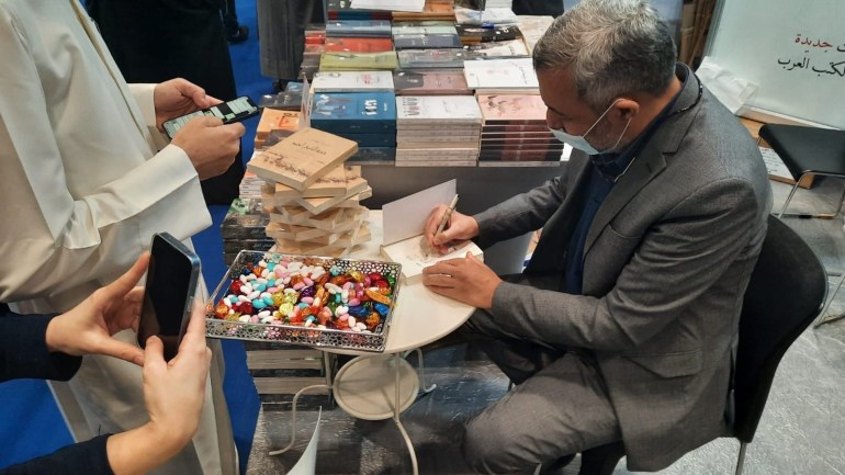 Novelist Issa Sheikh Hassan signs his novel at the Doha Book Fair 2021
