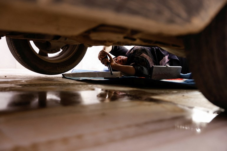 Mayson Hasaan, 38, an Iraqi woman who owns and runs a car repair garage, checks a car at her garage in Baghdad