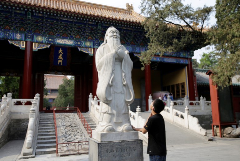 A student looks up at a Confucius statue at Confucian Temple in Beijing