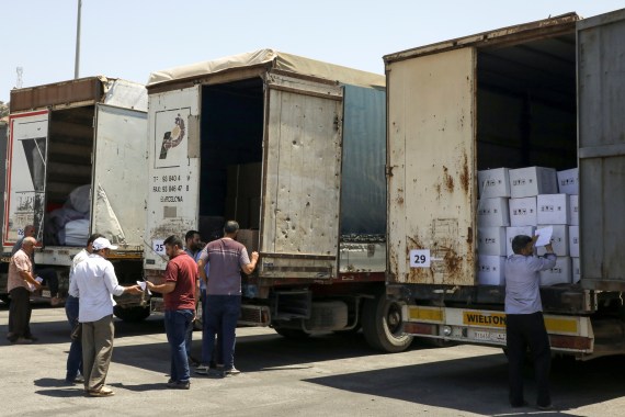 People stand near trucks loaded with humanitarian aid at Bab al-Hawa crossing at the Syrian-Turkish border, in Idlib governorate