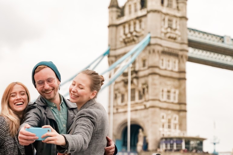 Happy friends travel in London with tower bridge and smile for a selfie, people caucasian beauty. Tourism, travel, people, leisure and teenage concept.