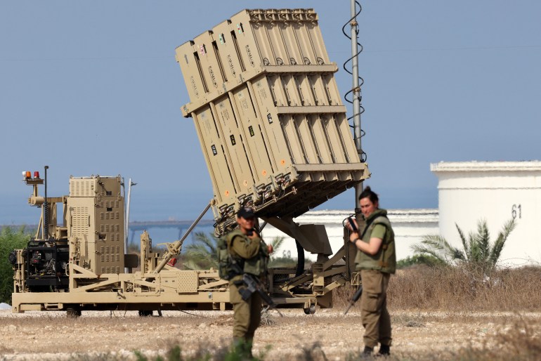 Israeli soldiers stand near a battery of Israel's Iron Dome defence missile system, designed to intercept and destroy incoming short-range rockets and artillery shells, deployed in Ashkelon in southern Israel on August 6, 2022. - Israel on August 6 hit Gaza with air strikes and the Palestinian Islamic Jihad militant group retaliated with a barrage of rocket fire, in the territory's worst escalation of violence since a war last year. Israel has said it was forced to launch a "pre-emptive" operation against Islamic Jihad, insisting the group was planning an imminent attack following days of tensions along the Gaza border. (Photo by Jack Guez / AFP)