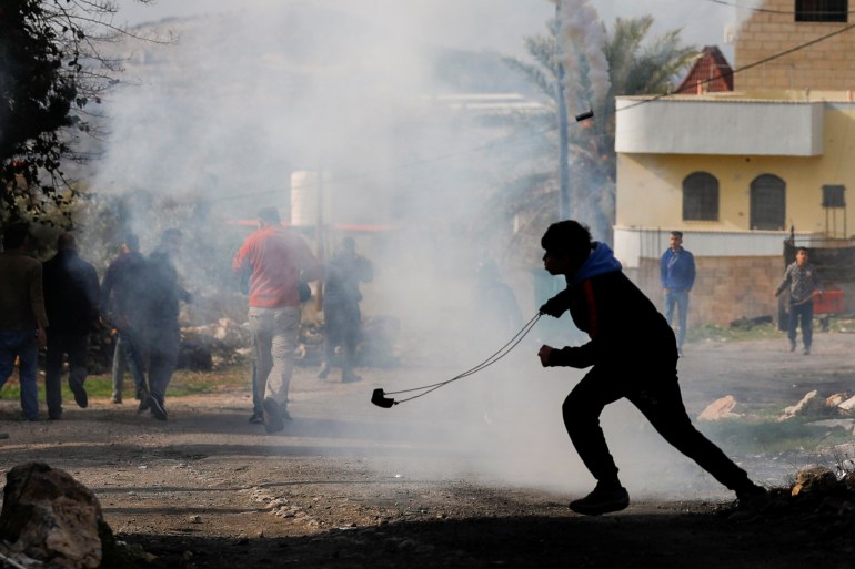 A Palestinian demonstrator runs away from tear gas fired by Israeli forces as Palestinians clash with Israeli troops during a rally marking the 57th anniversary of Fatah movement foundation and against settlements, near Nablus in the Israeli-occupied West Bank December 31, 2021. REUTERS/Mohamad Torokman