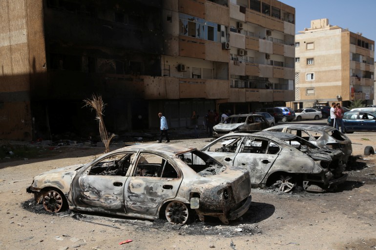 People gather next to burnt cars after yesterday's clashes in Tripoli, Libya August 28, 2022. REUTERS/Hazem Ahmed