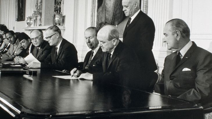 الرئيس ليندون بي جونسون (في أقصى اليمين) يتطلّع إلى جانبه بينما يوقع وزير الخارجية دين رسك معاهدة حظر انتشار الأسلحة النووية في العام 1968. (© Corbis/Getty Images)