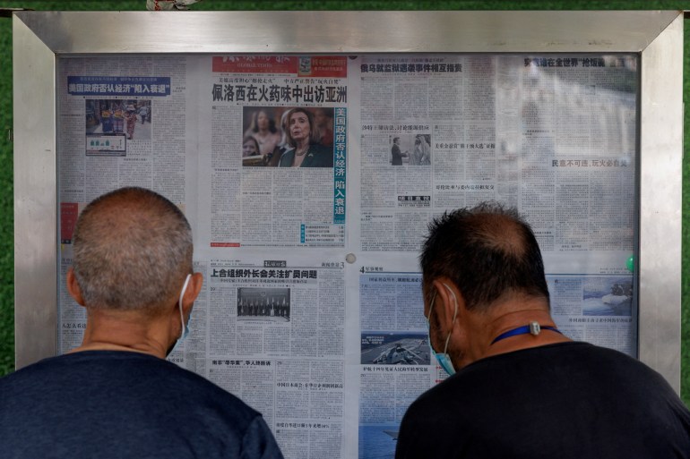 Men read a newspaper that features an article about U.S. House of Representatives Speaker Nancy Pelosi's Asia tour, in Beijing