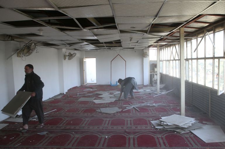 Afghans remove broken glass and piece of roof from a mosque near the site of a suicide bomb blast in Kabul, Afghanistan