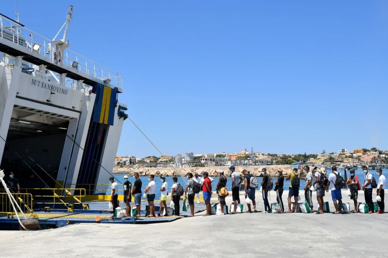 Migrants escorted by Italian authorities queue to board a ferry from the island of Lampedusa to SicilyALBERTO PIZZOLI/AFP