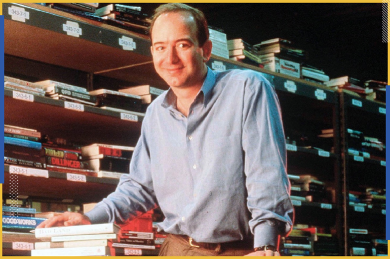صورة قديمة لجيف بيوزس مؤسس "أمازون" يقف بين الكتب في مراحل الشركة الأولى (مواقع التواصل)