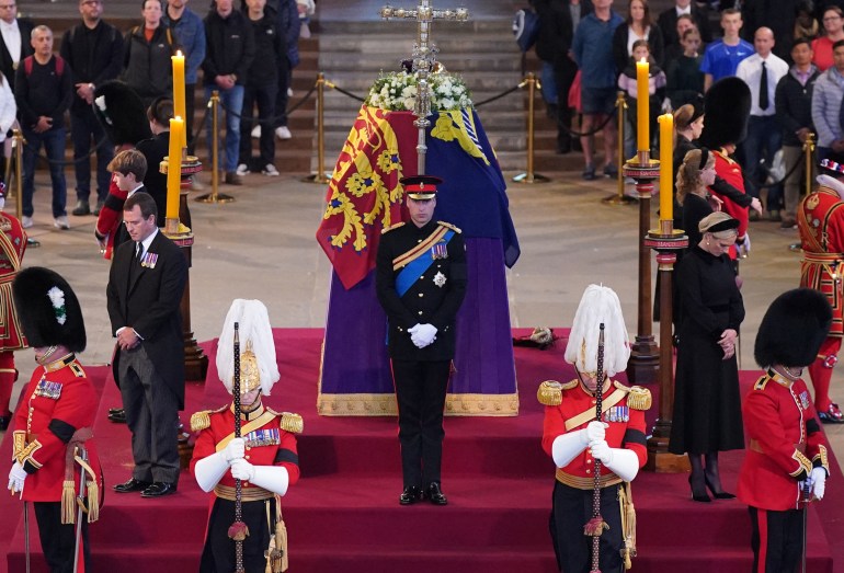 Queen Elizabeth II 's grandchildren (clockwise from front centre) Britain's Prince William, Prince of Wales, Peter Phillips, James, Viscount Severn, Britain's Princess Eugenie of York, Britain's Prince Harry, Duke of Sussex, Britain's Princess Beatrice of York, Britain's Lady Louise Windsor and Zara Tindall hold a vigil around the coffin of Queen Elizabeth II, draped in the Royal Standard with the Imperial State Crown and the Sovereign's orb and sceptre, lying in state on the catafalque in Westminster Hall, at the Palace of Westminster in London on September 17, 2022, ahead of her funeral on Monday. - Queen Elizabeth II will lie in state in Westminster Hall inside the Palace of Westminster, until 0530 GMT on September 19, a few hours before her funeral, with huge queues expected to file past her coffin to pay their respects. (Photo by Yui Mok / POOL / AFP)