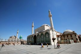 People visit the mausoleum of Jalal ad-Din Muhammad Rumi and the Selamiye mosque in Konya, Central Anatolia region, on August 17, 2016. - The face of President Recep Tayyip Erdogan is everywhere in Konya, a central Anatolian stronghold of his Islamic-rooted Justice and Development Party (AKP), that has enjoyed ever greater prosperity in his 13 years in power. "We are united with our commander-in-chief," says one giant banner on a building, as well as billboards and flags praising the man who has dominated Turkey since becoming premier in 2003 and then president from 2014. (Photo by ADEM ALTAN / AFP)