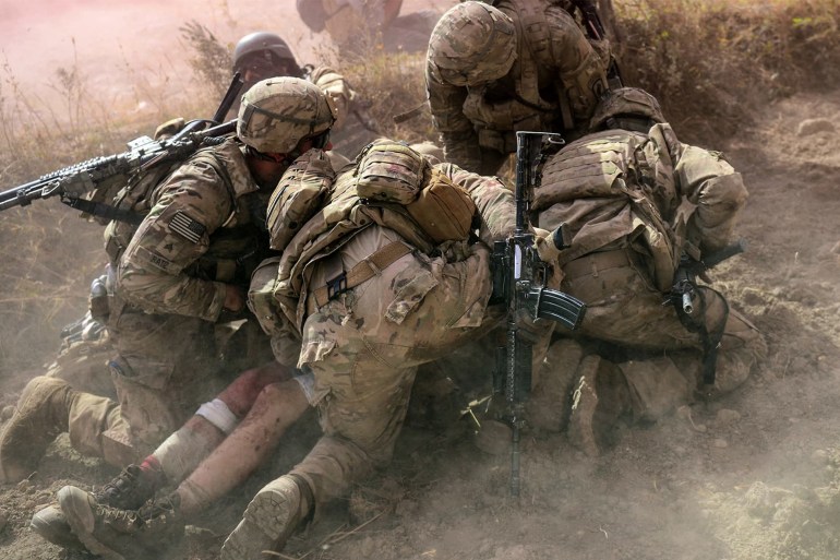 In this file photo taken on October 13, 2012, US Army soldiers attached to 2nd platoon, C troop, 1st Squadron (Airborne), 91st US Cavalry Regiment, 173rd Airborne Brigade Combat Team operating under Nato-sponsored International Security Assistance Force (ISAF) protect a wounded comrade from dust and smoke flares after an Improvised Explosive Device (IED) blast during a patrol near Baraki Barak base in Logar province. — AFP