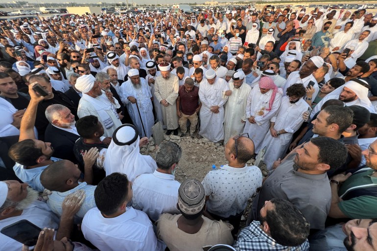 Family members and followers of Islamic scholar, Sheikh Youssef al-Qaradawi, gather around his grave for final prayers after his burial at a graveyard in Doha, Qatar, September 27, 2022. REUTERS/Imad Creidi
