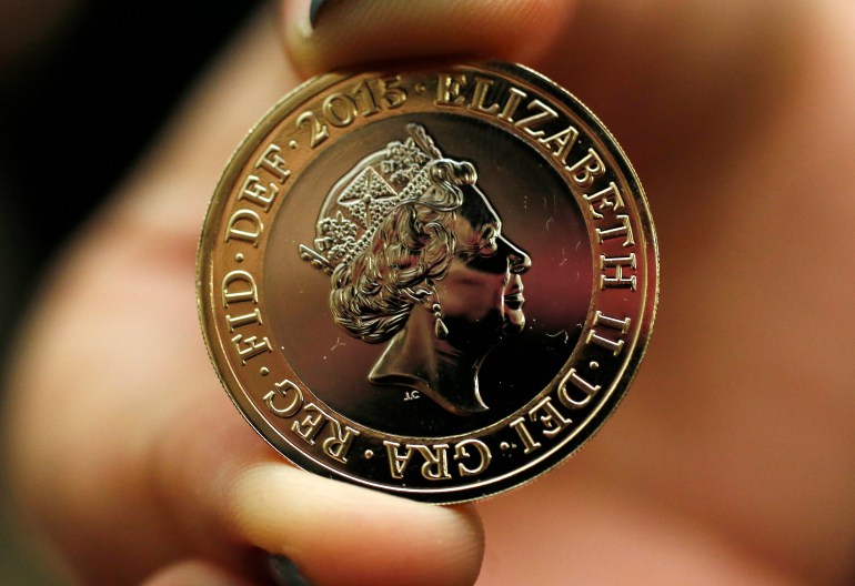 A gallery assistant holds a 2-pound coin with the new portrait of Britain's Queen Elizabeth following it's unveiling at the National Portrait Gallery in London March 2, 2015. This is the fifth portrait of the Queen to be used on a British coin during her reign. REUTERS/Suzanne Plunkett (BRITAIN - Tags: ROYALS BUSINESS)