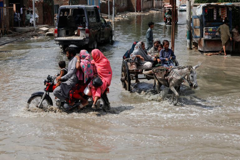 Commuters travel through rain waters, following rains and floods during the monsoon season in Jacobabad