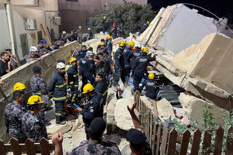 Civil defence members work at the site of a four-storey residential building collapse in Amman