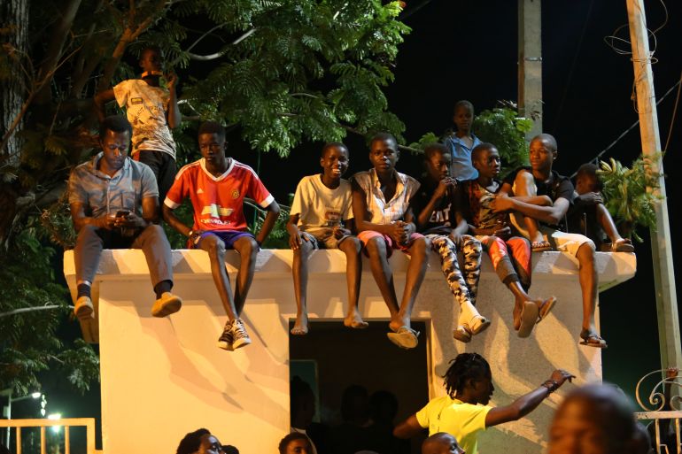 Children sit on top of a house gate by the presidential villa in Banjul
