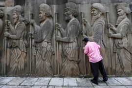 A Parsi man touches the walls of a Parsi fire temple featuring huge carvings of ancient priests during the Parsi New Year day in Mumbai