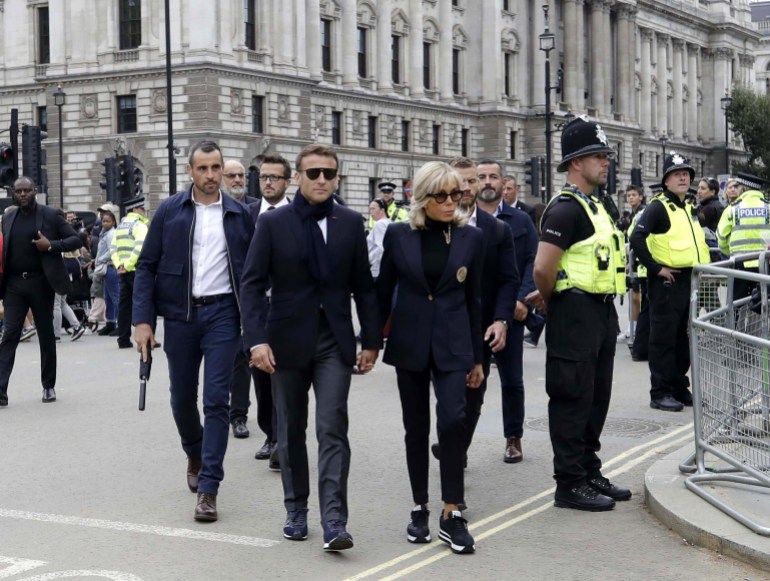 epa10191787 French President Emmanuel Macron (L) and his wife Brigitte Macron (R) walk in a street in London, 18 September 2022. The couple arrived in London to pay their respects to Britain's late Queen Elizabeth II. The queen's funeral will be held on 19 September, following four days of lying in state inside Westminster Hall. EPA-EFE/OLIVIER HOSLET
