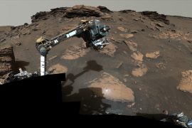 NASA’s Perseverance rover puts its robotic arm to work around a rocky outcrop called “Skinner Ridge” in Mars’ Jezero Crater. Composed of multiple images, this mosaic shows layered sedimentary rocks in the face of a cliff in the delta, as well as one of the locations where the rover abraded a circular patch to analyze a rock’s composition. Credits: NASA/JPL-Caltech/ASU/MSSS