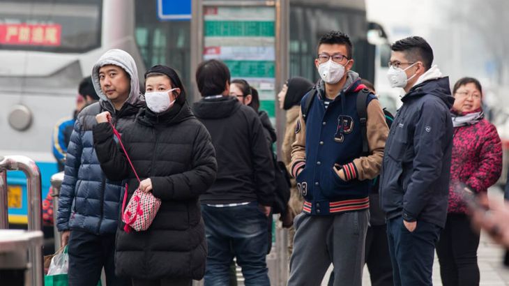 BEIJING, CHINA - DECEMBER 11, 2016: Unidentified people using facemask are seen at a bus stop in city downtown. Today, China's meteorological authorities issued a yellow alert for smog.