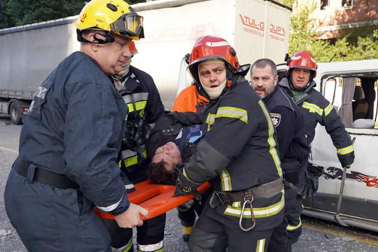 Rescuers carry an injured man on a stretcher at the site of shelling in Kyiv. [Handout via AFP]