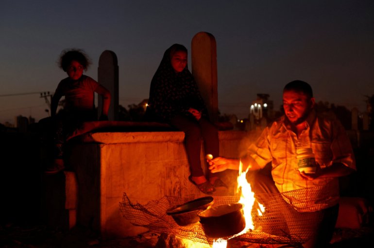The Kuhail family cook on a fire in the Sheikh Shaban cemetery. [Mohammed Salem/Reuters]