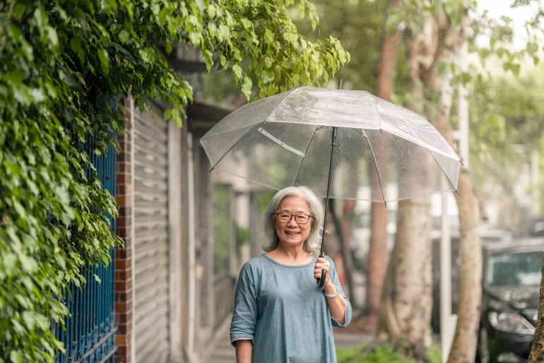A happy senior woman on the street of Taipei is looking into the camera.