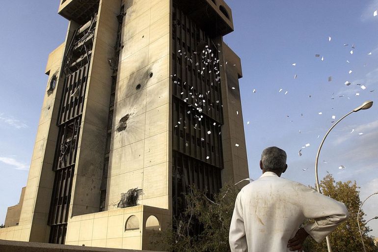 BAGHDAD - APRIL 10: An Iraqi man pauses to watch looters toss out government files from a destroyed Ministry building April 10, 2003 in downtown Baghdad, Iraq. Coalition forces have seized control of much of Baghdad although pockets of resistance remain. (Photo by Scott Nelson/Getty Images)