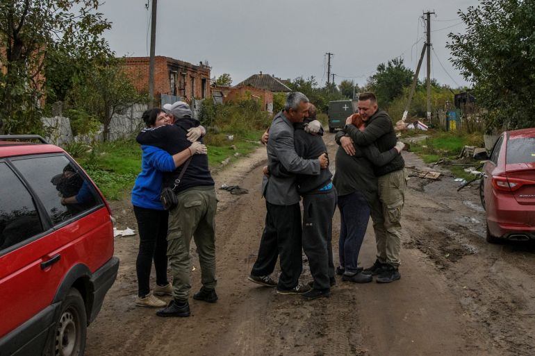 Neighbours embrace each others after they return from evacuation to liberated village in Kamianka