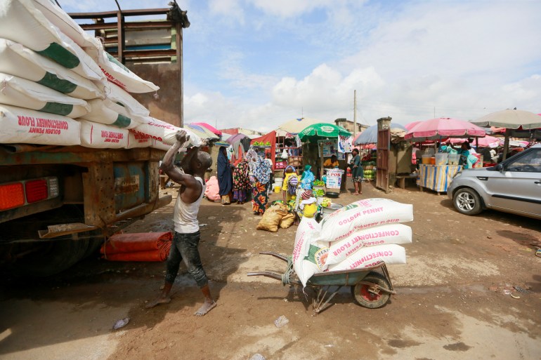 A man unloads bags of flour from a truck at Utako market in Abuja