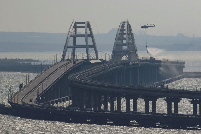 A helicopter drops water to extinguish fuel tanks ablaze on the Kerch bridge in the Kerch Strait, Crimea
