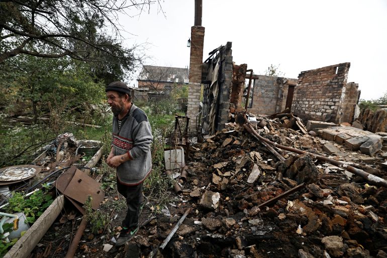 Mykola, 55, smokes a cigarette beside his neighbour's house, destroyed by Russian missile strike, amid Russia's attack on Ukraine, in the newly recaptured town of Oleksandrivka