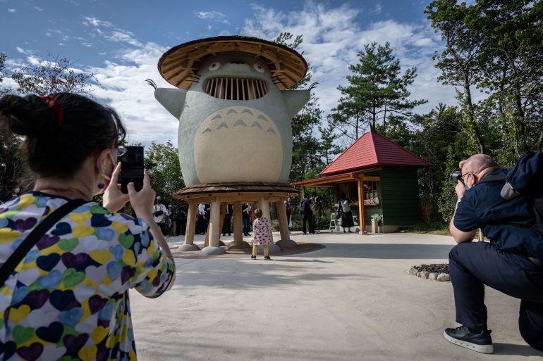 People take photographs of an exhibit of Ghibli character 'Totoro' at Dondoko Forest during a media tour of the new Ghibli Park in Nagakute, Aichi prefecture on October 12, 2022. - The media on October 12 got a sneak peek at the highly anticipated new theme park from Studio Ghibli, creator of beloved titles like "My Neighbour Totoro" and Oscar-winning "Spirited Away". (Photo by Yuichi YAMAZAKI / AFP) / EDITORS NOTE: MANDATORY CREDIT: ©?Studio Ghibli RESTRICTED TO EDITORIAL USE - MANDATORY MENTION OF THE ARTIST UPON PUBLICATION - TO ILLUSTRATE THE EVENT AS SPECIFIED IN THE CAPTION