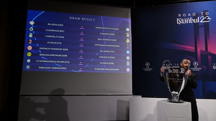 A man removes the UEFA Champions League trophy in front of a screen showing the draw result for the round of 16 of the 2022-2023 UEFA Champions League football tournament in Nyon on November 7, 2022. (Photo by Fabrice COFFRINI / AFP)