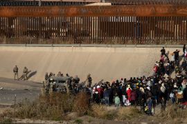 Migrants wait on the Mexican bank of the Rio Grande in Ciudad Juarez