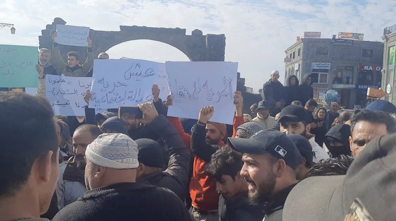 People hold placards as they gather during a protest in Sweida, Syria, December 4, 2022, in this screen grab obtained from a social media video. Suwayda 24/via REUTERS THIS IMAGE HAS BEEN SUPPLIED BY A THIRD PARTY. MANDATORY CREDIT. NO RESALES. NO ARCHIVES.