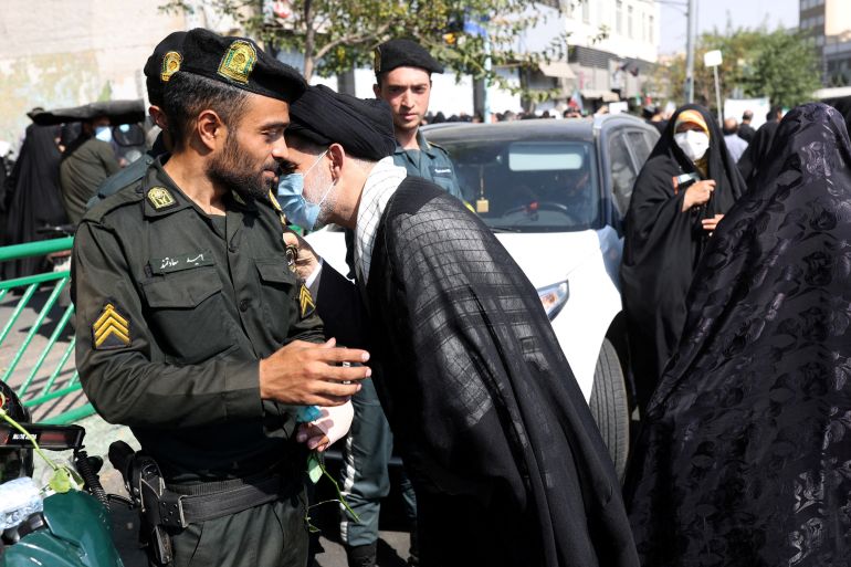 A pro-government cleric hugs a policeman during a rally against the recent protest gatherings in Iran, after the Friday prayer ceremony in Tehran