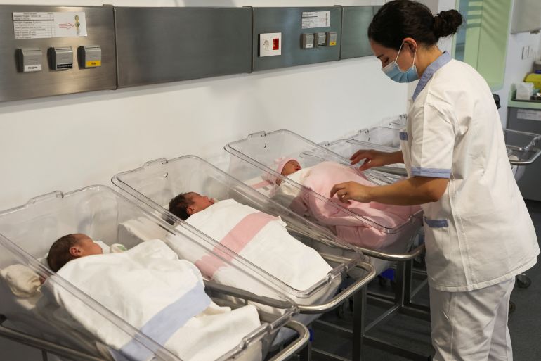 A medical worker stands near newborn babies at Hotel Dieu hospital as the world's population surged past 8 billion