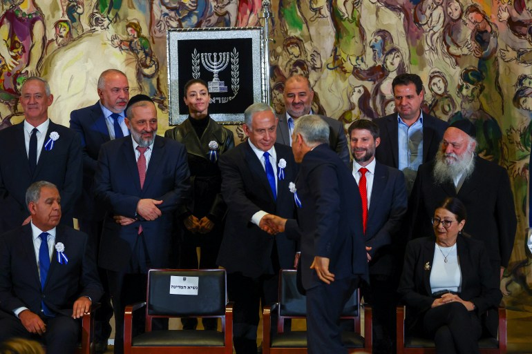 Netanyahu and Lapid shake hands before a group photograph with members of the new Israeli parliament after their swearing-in ceremony in Jerusalem