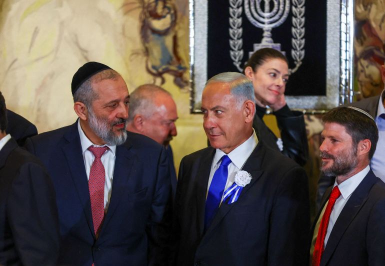 Netanyahu looks at Member of Knesset Deri as they stand with members of the new Israeli parliament after their swearing-in ceremony in Jerusalem