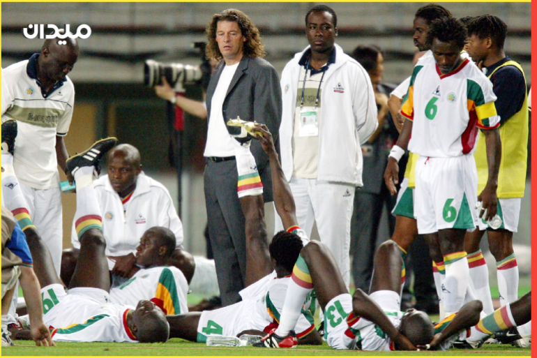 Senegal's coach Bruno Metsu stands between his team before extra time during their quarter-final match against Turkey at the World Cup finals in Osaka June 22, 2002. Turkey won the match with a golden goal four minutes into extra time against Senegal to send Turkey into the World Cup semi-finals for the first time on Saturday. Turkey will face four-times world champions Brazil in Saitama on Wednesday after Ilhan shot home on the half-volley from eight metres out. The two sides had failed to score in regulation time despite a fast-flowing match in which Turkey created the better chances against the African debutants. REUTERS/Kai Pfaffenbach JOH/JDP