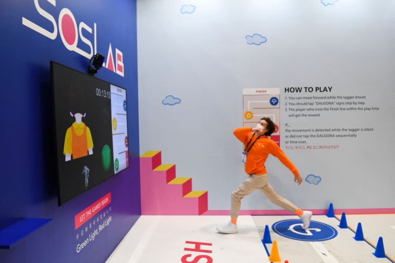 An attendee crosses the finish line while playing a LiDAR monitored game of Red Light Green Light at the South Korea-based SOS LAB company booth during the Consumer Electronics Show (CES) on January 6, 2022 in Las Vegas, Nevada. - The CES tech show threw open its doors Wednesday in Las Vegas despite surging Covid-19 cases in the United States, as one of the world's largest trade fairs tried to get back to business. Despite some obvious gaps on the showfloor -- after high-profile companies like Amazon and Google cancelled over climbing virus risk -- crowds of badge-wearing tech entrepreneurs, reporters and aficionados poured through venues. (Photo by Patrick T. FALLON / AFP)