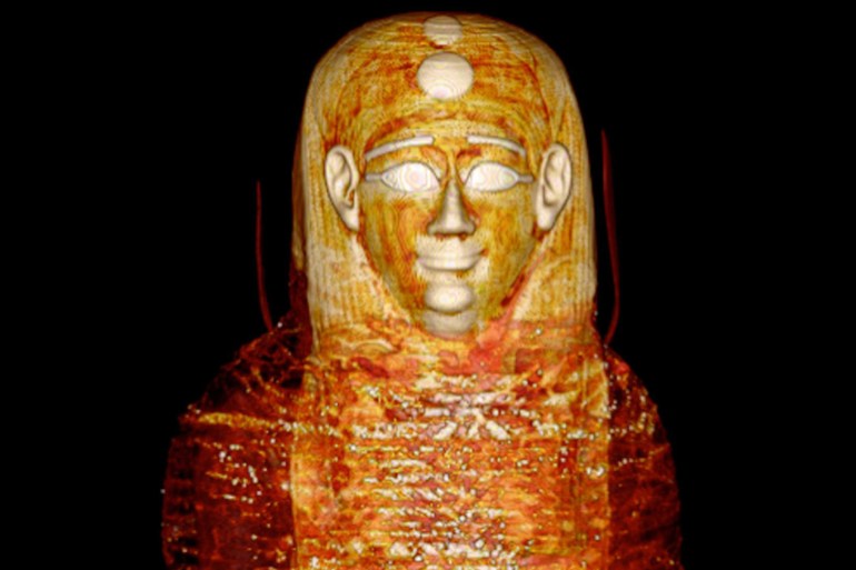 Figure 3. Three-dimensional computed tomography (CT) image of the front of the head and torso of mummy TR 21/11/16 at the Cairo Egyptian Museum showing the head mask and the most outer bandages arranged transversely (short arrow) and diagonally in a criss-cross orientation (long arrow).