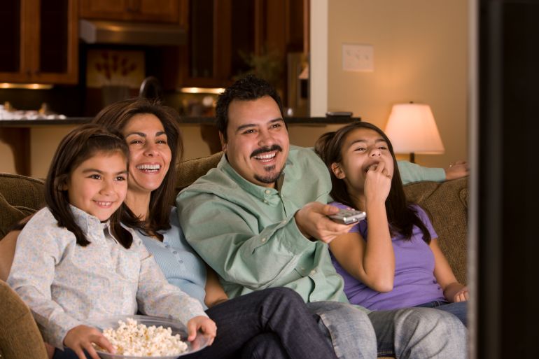 Hispanic family watching television together - stock photo GettyImages-88751879