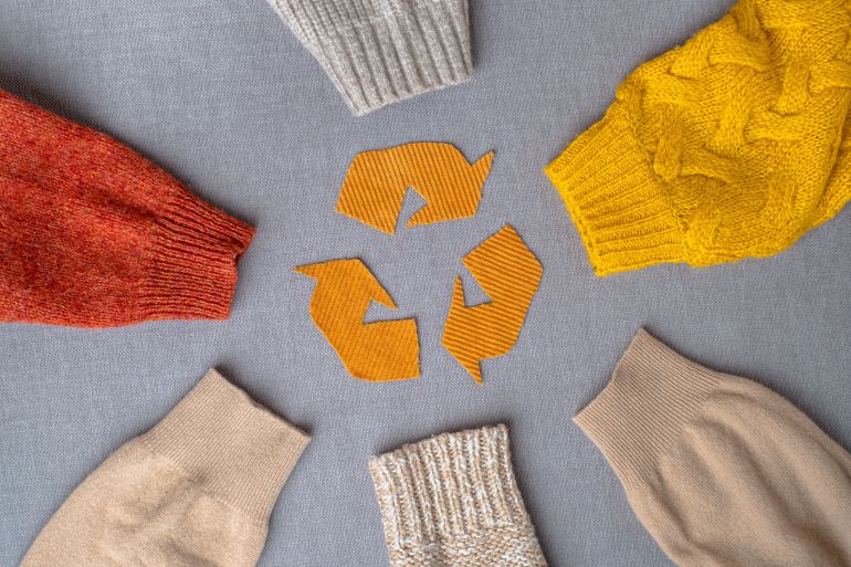 Clothing recycling. Used clothes. Ecological and sustainable fashion. sleeves of autumn woolen sweaters. ...