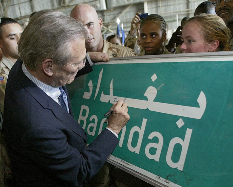 FILE PHOTO: U.S. Secretary of Defence Donald Rumsfeld signs a Baghdad road sign at the request of a U.S. soldier, April 30, 2003 during his visit to U.S. troops at Baghdad's international airport, Iraq. Rumsfeld paid a flying visit to Baghdad on Wednesday, 40 days after Washington went to war to overthrow Saddam Hussein. Luke Frazza/Pool via REUTERS/File Photo