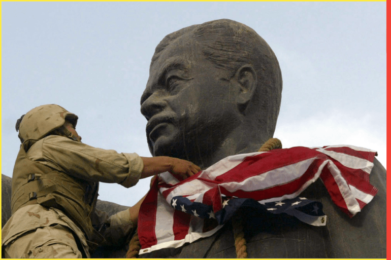 A U.S. Marine covers the face of a statue of Iraqi President Saddam Hussein with a U.S. flag in Baghdad April 9, 2003. U.S. troops briefly draped an American flag over the face of a giant statue of President Saddam Hussein in central Baghdad on Wednesday as they prepared to topple it in front of a crowd of Iraqis.The gesture, likely to be highly provocative in much of the Arab world where the U.S. invasion of Iraq has stirred widespread anger, was quickly reversed and an Iraqi flag was tied instead to the statue's neck.Local residents had earlier scaled the 20-foot (six metre) statue and slipped a noose around its neck to drag it down.