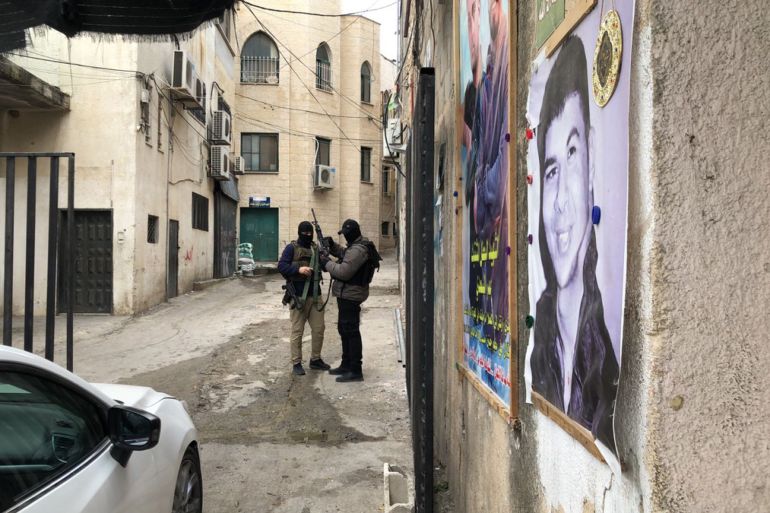 صورة رقم 2 فلسطين 8 مارس مخيم جنين فاطمة محمود الجزيرة نت مقاتلان يزودان سلاحيهما بالذخيرة خلال تشييع الشهداء_